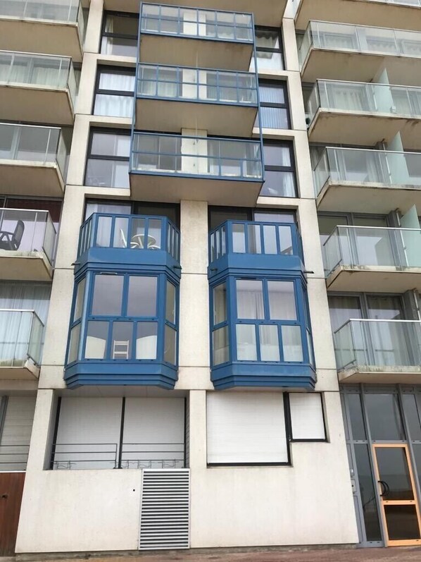 A multi-story building with balconies, large windows, and a central air conditioning unit.