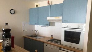 A compact kitchen with blue cabinets, a white stove, and a dishwasher. - Apartment with sea view (Bray-Dunes)