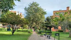 A paved pathway in a park-like setting with benches and greenery.