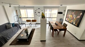 A modern living room with a sofa, coffee table, and a dining area with chairs and a table.
