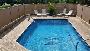 A rectangular swimming pool with a tiled deck, surrounded by a bamboo fence. - Private Cozy Studio walking distance to beaches, shops, restaurants and bars (Kihei)
