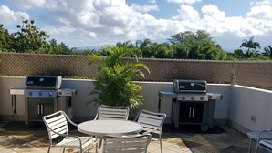 An outdoor patio with two barbecue grills, a round table, and four chairs. - Private Cozy Studio walking distance to beaches, shops, restaurants and bars (Kihei)