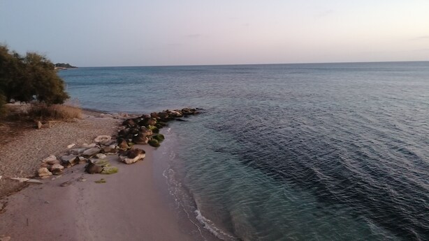 A beach with clear water, a rocky shoreline, and sparse vegetation. - Apartment with sea view terrace, parking and garden. (Cagliari)
