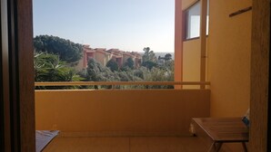 A balcony with a view of a residential area, a wooden table, and a chair. - Apartment with sea view terrace, parking and garden. (Cagliari)