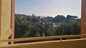 A balcony with a view of a coastal area, including buildings and trees. - Apartment with sea view terrace, parking and garden. (Cagliari)
