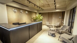 A modern reception area with a reception desk, seating area, and a plant. - Bakuriani Crystal Loft 406 (Borjomi)