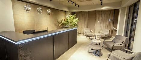 A modern reception area with a reception desk, seating area, and a plant.