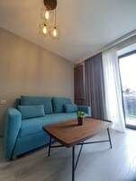 Una sala moderna con un sofá azul, una mesa de centro de madera y una lámpara colgante de diseño geométrico.
