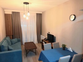Una sala moderna con un sofá, una mesa de centro, un televisor y un comedor con sillas y una mesa.