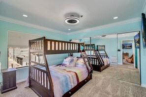 Une chambre avec des lits superposés, un grand miroir et une vue par la fenêtre.