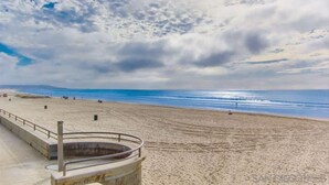 Une plage avec une promenade en béton et une rambarde en métal.