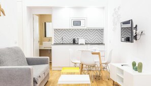 A modern kitchen with white cabinets, a microwave, and a coffee machine.