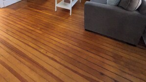 A living room with a flat-screen TV, a white coffee table, a grey sofa, and a wooden floor. - Saugerties Village Space with Great Backyard (Saugerties)