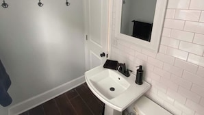 A bathroom with a white sink, mirror, and toilet. - Saugerties Village Space with Great Backyard (Saugerties)