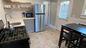 A modern kitchen with a gas stove, stainless steel refrigerator, and wooden shelves. - Saugerties Village Space with Great Backyard (Saugerties)