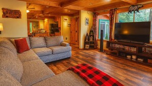 Una sala de estar acogedora con un sofá modular, un televisor de pantalla plana y una chimenea.