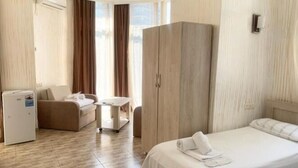 A hotel room with a bed, a desk, a chair, a wardrobe, and a small table. - Batumi Hall (Batumi)