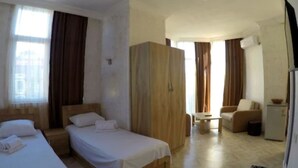 A hotel room with two beds, a wardrobe, a small table, a sofa, and a refrigerator. - Batumi Hall (Batumi)