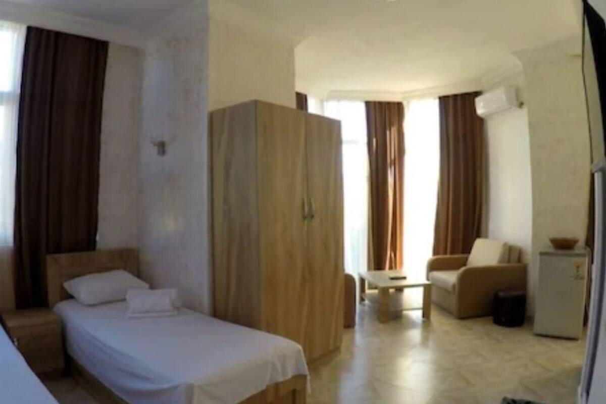 Habitación de hotel con dos camas, un armario, una mesita, un sofá y un refrigerador.