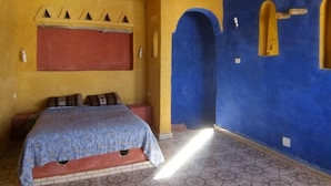Ein Zimmer mit einem Bett, einer roten Wand, einer blauen Wand und einem gemusterten Boden.