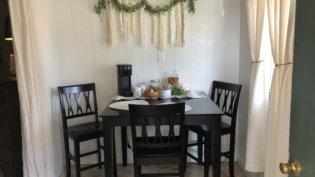 A dining area with a table set for four, a coffee maker, and a decorative garland on the wall. - Tiny casita in beautiful Uvalde, 20 minutes from Frio River (Uvalde)