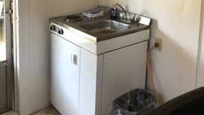 A compact kitchen with a built-in dishwasher, a stainless steel sink, wooden cabinets, and a trash bin. - Tiny casita in beautiful Uvalde, 20 minutes from Frio River (Uvalde)