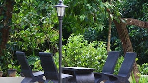 A garden setting with a table and four chairs, surrounded by lush greenery and a single street lamp. - Heaven villa (mirissa)
