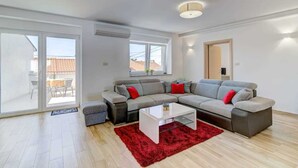 Una sala de estar moderna con un sofá seccional gris, una mesa de centro blanca y un tapete rojo.