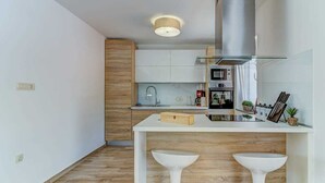 Una cocina moderna con armarios blancos, una campana extractora de acero inoxidable y una encimera blanca.