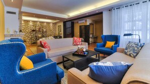 A spacious living room with a sofa, armchairs, and a coffee table. There is a stone wall and a fireplace in the background. - Villa Luxview 17 Bribir (Bribir)