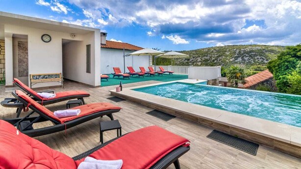 A rooftop pool area with lounge chairs, a clock, and a view of the surrounding landscape. - Villa Luxview 17 Bribir (Bribir)
