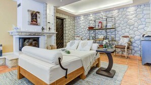 A cozy living room with a fireplace, a sofa, a coffee table, and a stone accent wall. - Villa Luxview 17 Bribir (Bribir)
