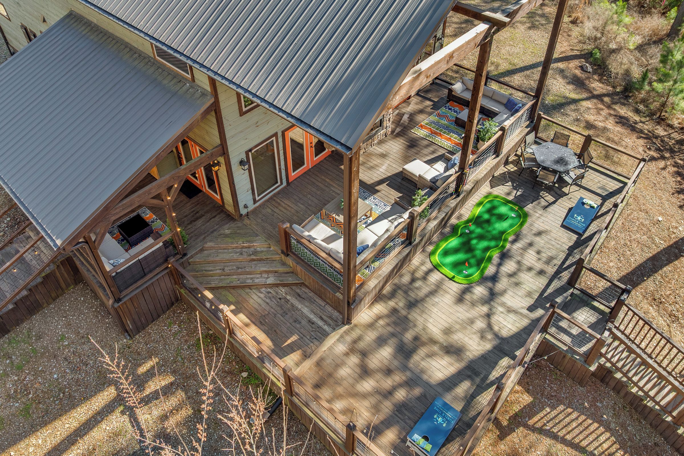 Une terrasse en bois avec un espace salon couvert, un barbecue et une piscine gonflable verte.