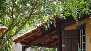 A stone pathway leading to a wooden structure with a tiled roof, surrounded by lush greenery and plants. - Chale Ipe Jatoba (Alto Paraíso de Goiás)