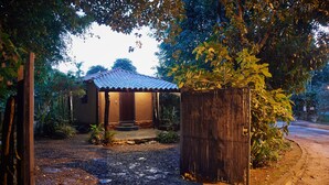 A rustic house with a tiled roof, surrounded by lush greenery and a gravel path leading to the entrance. - Chale Ipe Jatoba (Alto Paraíso de Goiás)