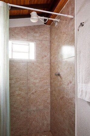 Une douche avec une fenêtre, des murs carrelés et un porte-serviettes.
