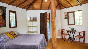 A room with a bed, a table with chairs, and a wooden ceiling. - Chale Ipe Jatoba (Alto Paraíso de Goiás)
