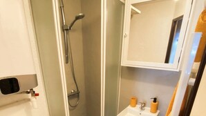 A bathroom with a shower, toilet, sink, and a mirror.