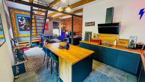 A modern kitchen with a wooden island, blue cabinets, and a brick wall. - Le Petit Majorelle Français, Swimming pool Garden Terrace, near city center. (Lavalette)