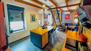 A modern kitchen with a wooden island, a dining area with a table and chairs, and a staircase leading to an upper level. - Le Petit Majorelle Français, Swimming pool Garden Terrace, near city center. (Lavalette)