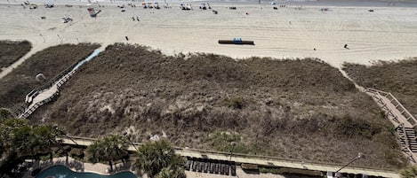 A beach resort with a swimming pool, a boardwalk, and a beach area.