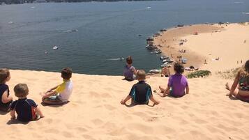 A beach with children sitting on the sand, boats in the water, and a clear view of the shoreline.