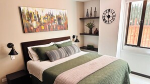 Ein ordentlich eingerichtetes Schlafzimmer mit Bett, Nachttischen, einer Wanduhr und einem Stadtbild.