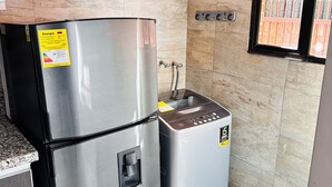 Eine kompakte Küche mit Edelstahl-Kühlschrank, einem eingebauten Backofen und einem Spülbecken.