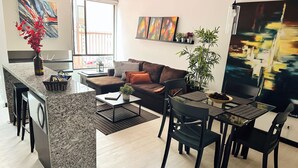 Ein modernes Wohnzimmer mit Küchenbereich, ausgestattet mit einer Couch, einem Esstisch und Stühlen.