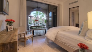 A hotel room with a bed, a desk, a chair, a small table, and a view of palm trees and a pool through a glass door. - Breathtaking Views, Private Pool/Spa adjacent to One&Only Palmilla!! (San José del Cabo)
