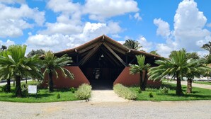 A building with a red brick facade, a sloped roof, and a central entrance. - CONDOMÍNIO FAZENDA TRÊS TESOUROS (Bonito)