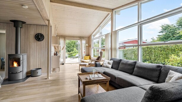 A modern living room with a large gray sectional sofa, a wooden coffee table, and a wood-burning stove. - Lovely home in Haderslev with WiFi (Haderslev)