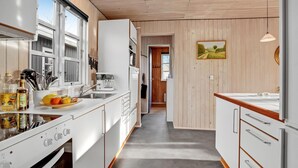 A modern kitchen with white cabinetry, a stainless steel sink, and a coffee maker. There is a fruit bowl on the counter and various kitchen utensils. - Lovely home in Haderslev with WiFi (Haderslev)