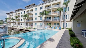 Un hotel con piscina, varios balcones y palmeras.